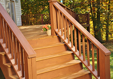 Stained outdoor staircase with woods in background.