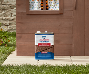 Can of Thompson’s WaterSeal Solid Color Wood Sealer in Chestnut Brown sitting in front of a children’s playhouse