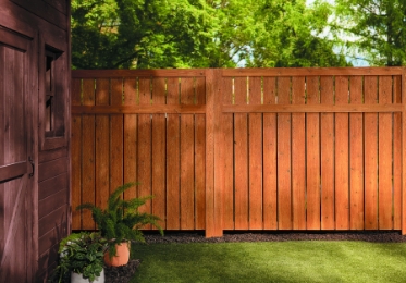 Stained backyard fence, half in shadow, half in sunlight.