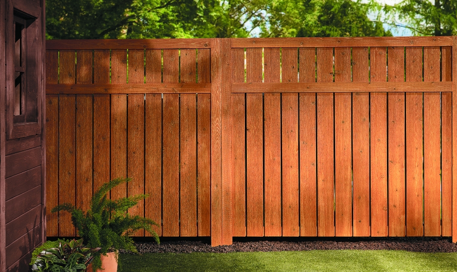 Stained fence half in shadow, half in sunlight. 