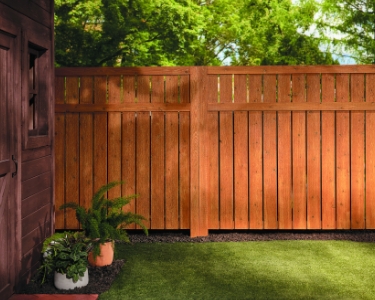 Stained fence half in shadow, half in sunlight. 