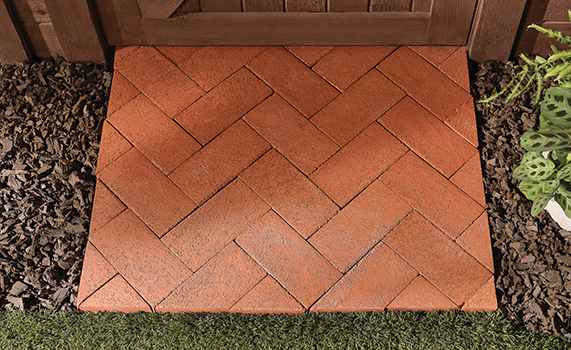 Herringbone-patterned brick paver square in clay red. 