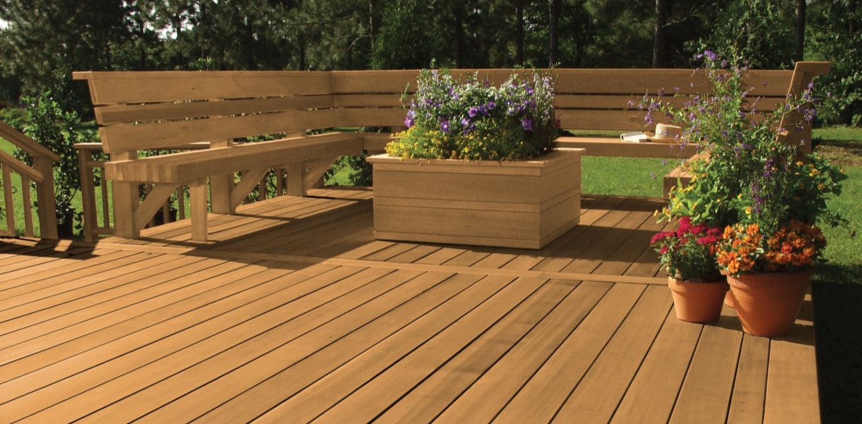 Outdoor wood deck with benches and flower planters, highlighting a well-protected surface with a natural wood grain appearance.